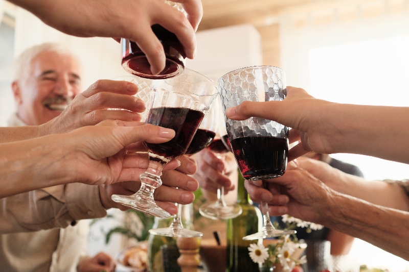 Close-up of happy people toasting with glasses of red wine during holiday dinner